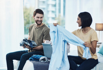 Couple, happy and folding laundry in home for support, shared chores and relationship responsibility on bed. Man, woman and clothes in bedroom for spring cleaning, sorting and housework on weekend
