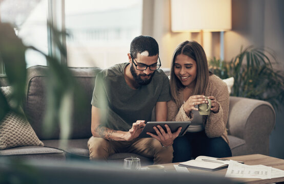 Home, happy couple and digital with tablet for finance, track expenses and success for bank loan. Coffee, woman and man with online budget for taxes review, handle savings and mortgage bills on sofa