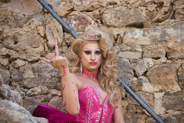 Eccentric blonde drag queen dressed in pink makes angry and disgusted face and raises her middle finger with the sign of fuck you dissatisfied with society. Concept of equality and lgtbqi+ rights.