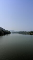 Calm river flowing through lush green landscape under clear blue sky.