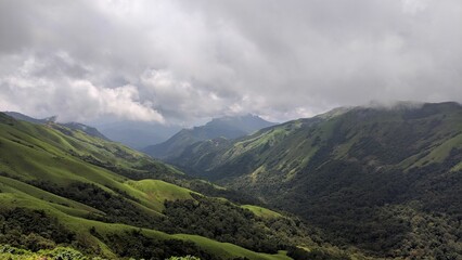 Lush green mountains in the Western Ghats under a cloudy sky. © Wirestock