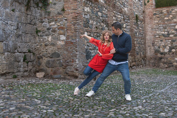 Couple dancing together on cobblestone street with rustic stone wall