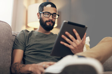 Sofa, man and relax with tablet for online, streaming video and social media with smile at home. House, male person and comfortable with digital for reading blog, application subscription and connect