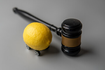 A lemon with wheels and a judge gavel. Lemon law concept.