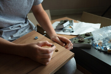 teenager assembles furniture according to instructions