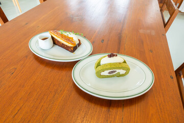 Matcha Green Tea Roll Cake and Salted caramel banana cake on wooden table,homemade bread cake,top view from above, space for text.
