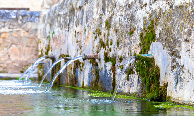 A stone wall with a water fountain that has many spouts