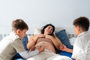 Fototapeta premium Caucasian family of pregnant mother and her two children painting her belly