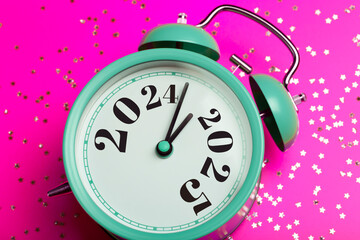 New Year 2025 background concept. 2024 changes to 2025 on an alarm clock on a colored background with festive glitter on New Year's Eve and Christmas.