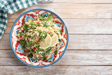 Tabbouleh salad with couscous on wooden table. Traditional lebanese food. Top view. Copy space