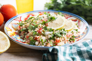 Tabbouleh salad with couscous on wooden table. Traditional lebanese food
