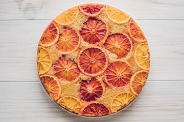 Delisious freshly baked homemade blood orange upside-down cake on white wooden background, top down view. Popular winter holiday dessert.