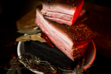 Smoked lard with meat on fire in a plate on a black background. Ukrainian cuisine concept. boiled pork.lard on smoke.Grilled lard