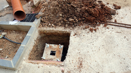 Workers laying communication lines on a construction site with open trenches and equipment in progress during daylight hours