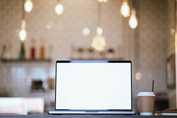 Blank laptop screen on wooden table with coffee shop interior background and blurred bokeh lights. Mockup model. Template for your text.