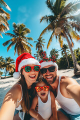 Happy young family wearing Santa&rsquo;s hats and Christmas sunglasses takes a selfie on the beach against the backdrop of palm trees. Winter holidays in exotic resort, travel photo in a tropical paradise. 