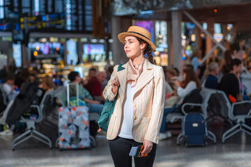 Caucasian young woman in straw hat holds passport with boarding pass. Check flight. The concept of vacation and flight trip