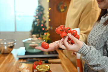 Close up of young woman choosing fresh tomatoes for a holiday dish