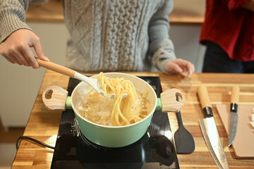 Young couple cooking pasta in a green pot on a stove during the festive season