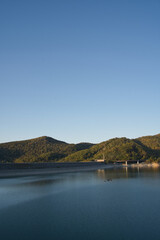 Fototapeta premium 北海道旭川市の忠別湖にある忠別ダムの秋の紅葉と夕暮れ時の湖面と青空