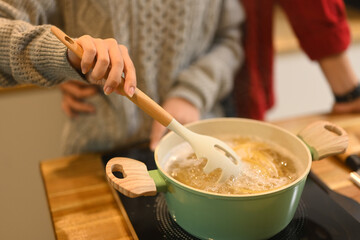 Close up of couple cooking pasta together in a warm kitchen during the festive season