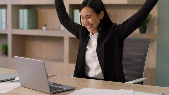 Excited happy Asian Japanese businesswoman female worker Chinese Korean business woman girl using laptop pc crossed fingers wish hope praying winning victory celebrating success cheering yes in office