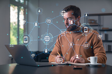 Man working on laptop with network icons overlay in modern office environment.