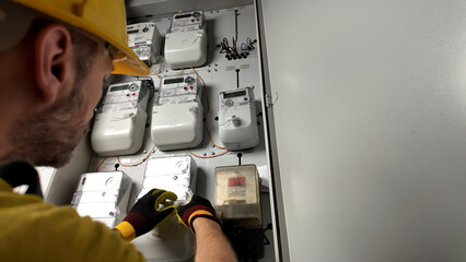 Technician working on a modern electricity power meter station in a building.