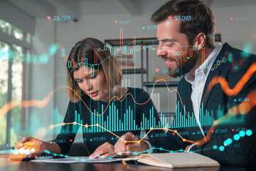 Two people analyzing data with financial graphs overlay in a modern office setting.
