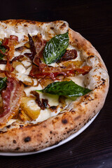 Pizza tradizionale napoletana con mozzarella, melanzane, patate al forno, pancetta croccante e basilico fresco servita in una pizzeria elegante