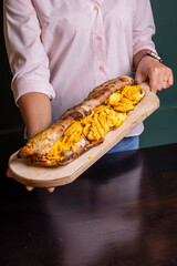 Panuozzo tradizionale napoletano con cheesesteak di manzo, provola , patate fritte e cheddar fuso servito su un tagliere di legno in un pub