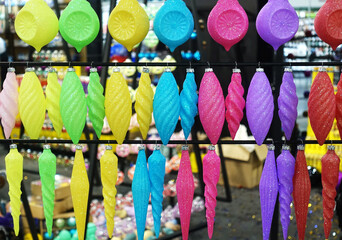 Rows of colorful Christmas baubles and icicles hang on a stand