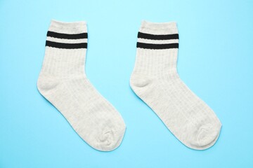 Pair of soft comfortable socks on light blue background, top view