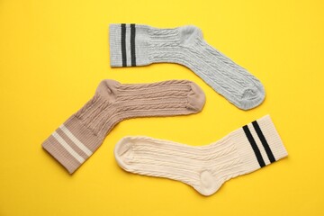 Different comfortable socks on yellow background, flat lay