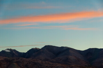 Serene Altai Mountains captured in autumn, featuring a picturesque sunset sky with vibrant hues of pink and blue in the background.