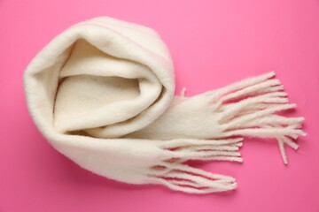 Warm woolen scarf on pink background, top view