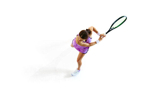 Focused, female tennis player in top-down shot, her eyes fixed on ball against white studio background. Concept of professional sport, championship, active lifestyle, tournament. Ad