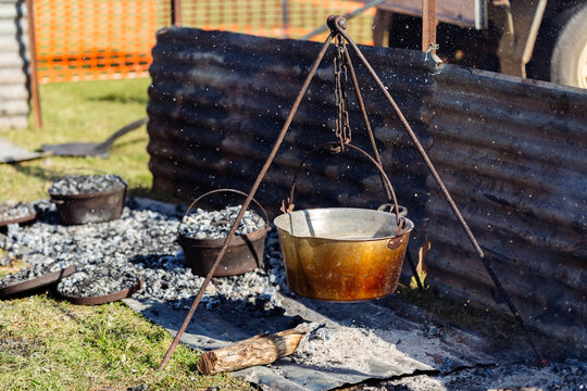 camp oven cooking damper bread on fire coals shielded by corrugated iron