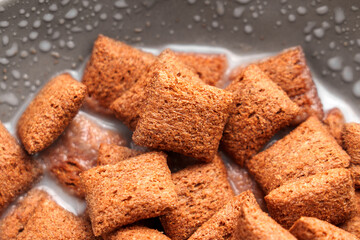 Brown cereal chocolate pillows in milk with bubbles on the surface, capturing a satisfying breakfast scene with contrasting textures and creamy appeal. Top View