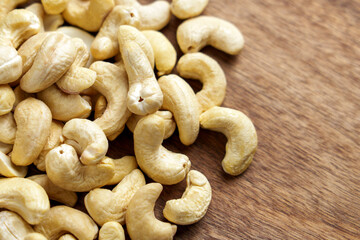 Cashews scattered on a wooden table with creamy color and smooth texture, ideal for a healthy snack or recipe ingredient. 