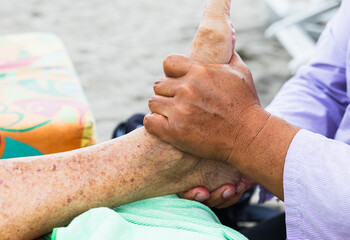 Elderly woman receiving therapeutic foot massage outdoors