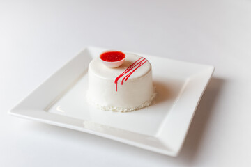 Colorful layered mousse cakes topped with fresh berries, decorative chocolate, standing on white plate isolated on  white background.