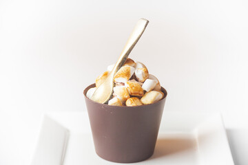 A glass made from chocolate milk with a chocolate spoon and marsmellows on white plate isolated on white background, concept for menus or recipe 