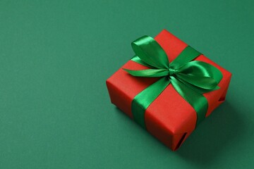 Beautiful gift box tied with golden bow on color background 