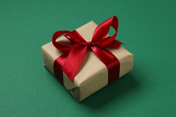 Beautiful gift box tied with golden bow on color background 