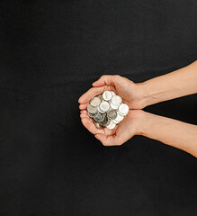 Coins in palms. Donation, charity, financial plan concept, trust fund, pension concept. Black background.