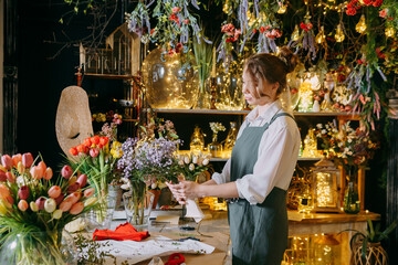 A woman in her florist shop collects bouquets of flowers. The concept of a small business. Bouquets of tulips for the holiday on March 8.