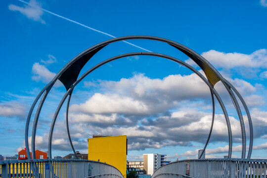 The image captures an artistic metal archway over a bridge, set against a vibrant blue sky, blending industrial design with contemporary urban aesthetics  in London UK