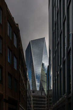 The image highlights a skyscraper with a striking angular glass facade, perfectly contrasting against overcast gray skies, symbolizing urban progress and architectural design  in London UK