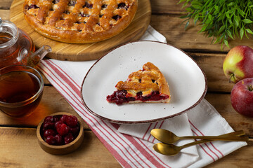 Cherry pie with fresh berries. Cake shovel with piece of pie on white plate on rustic wooden background. Sweet summer dessert, halves of ripe cherry.